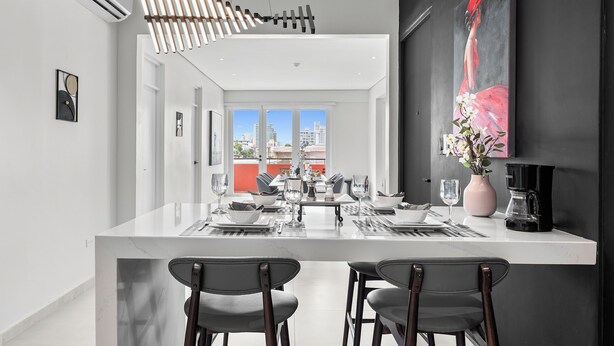 A modern kitchen with a white marble island, two bar stools, and a coffee machine. - Casa Placita Hotel (San Juan)