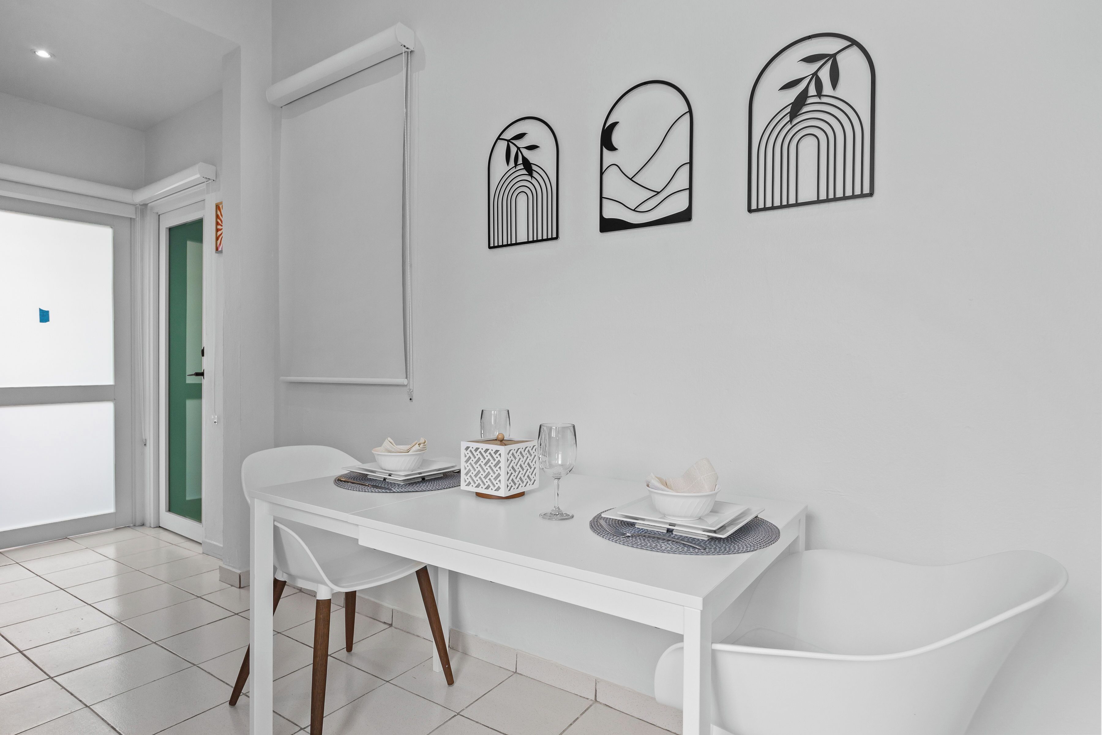 A modern dining area with a white table, chairs, and wall art.