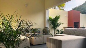 A modern outdoor living area with a sofa, a coffee table, and potted plants. - 2BR ground level Villa at a TOP location with private Pool ! (Noord)
