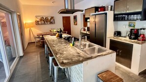 A modern kitchen with a central island, stainless steel appliances, and a bar stool. - 2BR ground level Villa at a TOP location with private Pool ! (Noord)