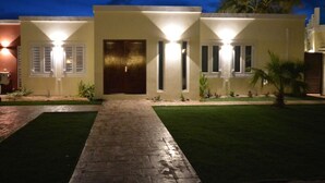 A modern two-story house with a paved driveway leading to a dark wooden door. - 2BR ground level Villa at a TOP location with private Pool ! (Noord)