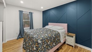 A bedroom with a bed, a nightstand, a window with curtains, and a blue accent wall. - Red Fox Den-Year Round Retreat At Massanutten- Ski, Bike, Golf, Hike & Waterpark (McGaheysville)