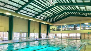 An indoor swimming pool with clear lanes, a high ceiling with skylights, and a view of the upper level with exercise equipment. - Red Fox Den-Year Round Retreat At Massanutten- Ski, Bike, Golf, Hike & Waterpark (McGaheysville)