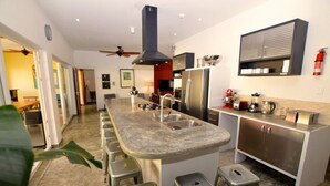 Una cocina moderna con una isla central, electrodomésticos de acero inoxidable y un ventilador de techo.