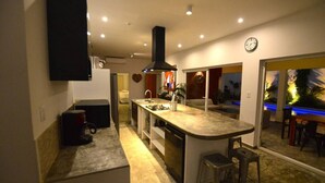 Una cocina moderna con una isla central, electrodomésticos integrados y vistas a una zona de piscina exterior.