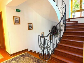 Eine Treppe mit aufwendiger Metallreling und einem gemusterten Teppich am Fuß.