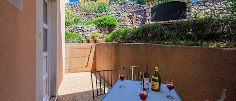 A patio with a table set for two, two wine glasses, and two bottles of wine.