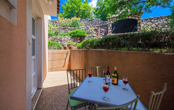 Eine Terrasse mit Tisch für zwei Personen, zwei Weingläsern und zwei Weinflaschen.
