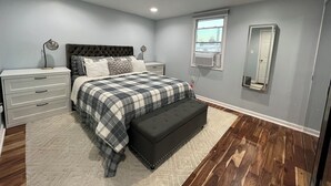 A bedroom with a bed, bedside tables, a mirror, and a window.