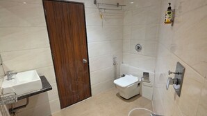 A bathroom with a sink, toilet, and shower. - Hotel Wellingten (Mumbai)
