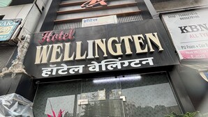 A hotel sign with the name "Wellington" and a logo above it. - Hotel Wellingten (Mumbai)