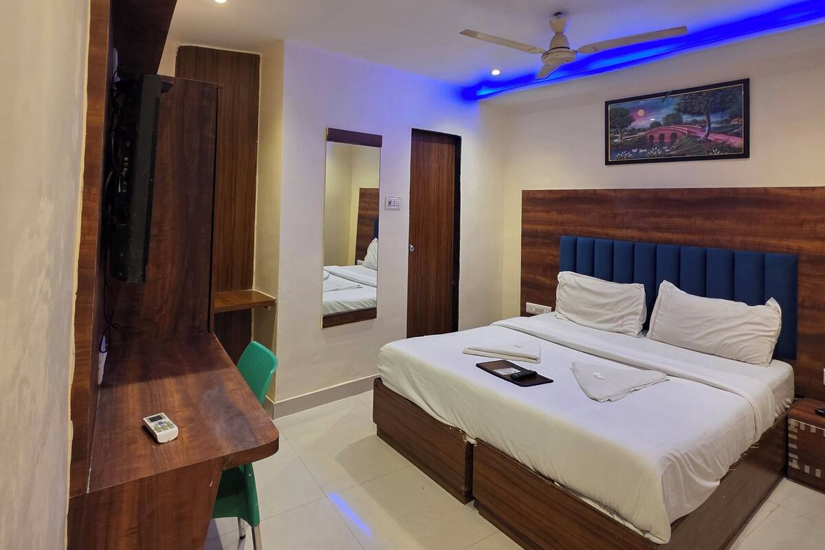 Une chambre à coucher avec un lit, un bureau, une chaise, un ventilateur de plafond et un tableau accroché au mur.