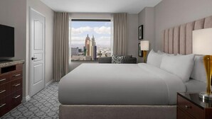 A hotel room with a large bed, a television, a desk with a lamp, and a view of a city skyline. - Steps from the Las Vegas Strip Perfect Condo for National Rodeo Finals Event (Las Vegas)