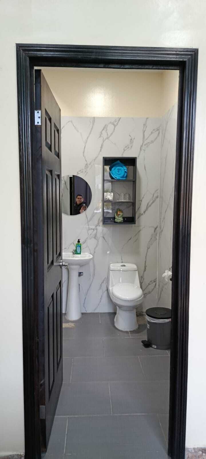 Une salle de bain équipée de toilettes, d’un lavabo et d’une petite étagère où sont rangés les articles de toilette.