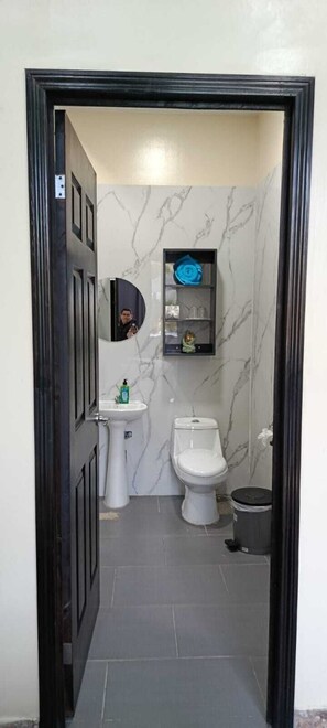 A bathroom with a toilet, sink, and a small shelf with toiletries. - Mi Tierra Surf City Hotel and Restaurant (La Libertad)
