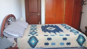 A bedroom with a bed, a wooden wardrobe, and a door. - Beautiful, comfortable, strategically located near to everything in Quito (Quito)