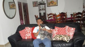 A person sitting on a black leather sofa with red and white patterned cushions, holding a small dog. - Beautiful, comfortable, strategically located near to everything in Quito (Quito)