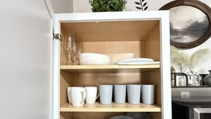 Ein Schrank mit Regalen, der Teller, Schüsseln und Tassen beherbergt.