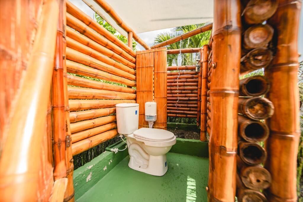 A bamboo-walled bathroom with a toilet and a handwashing station.
