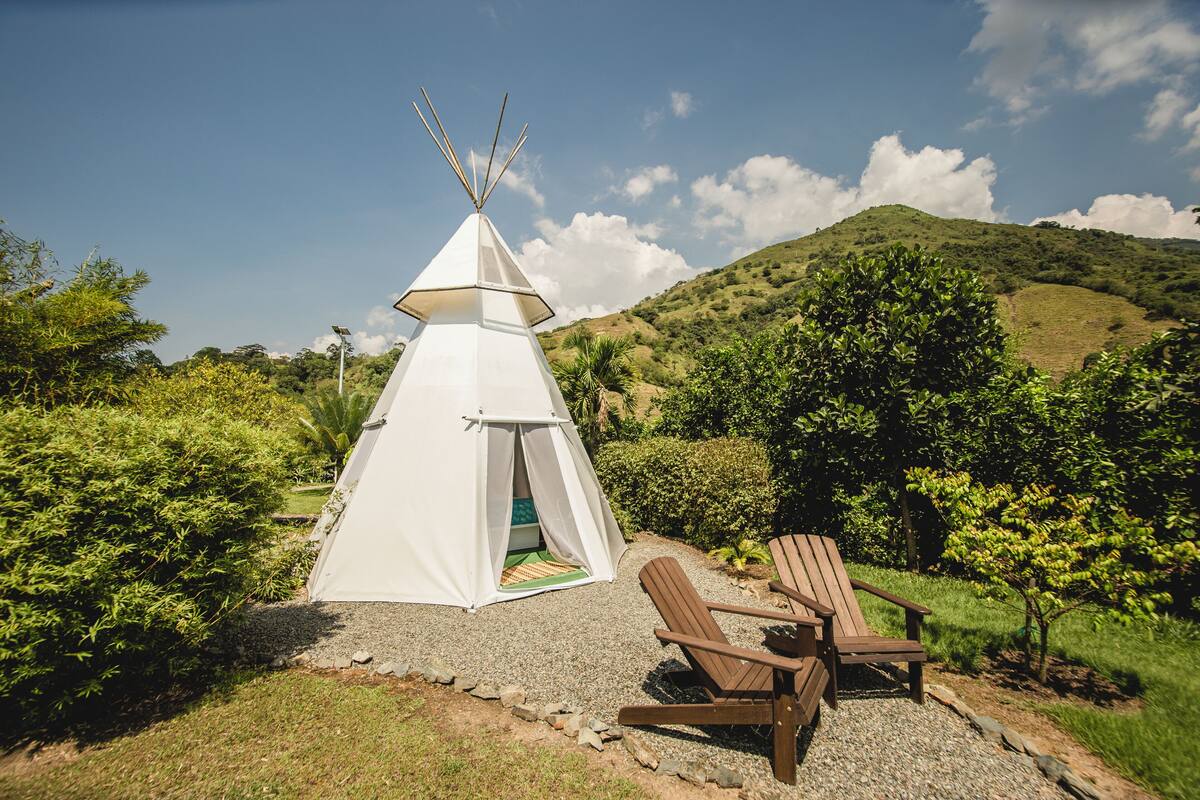 A white tent with a conical roof, a wooden chair, and a gravel path.