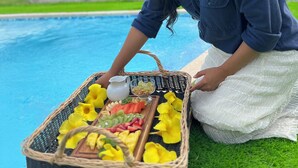 A person by a pool with a picnic basket containing fruits and a jug. - Cerro Tusa Glamping  (Titiribí)