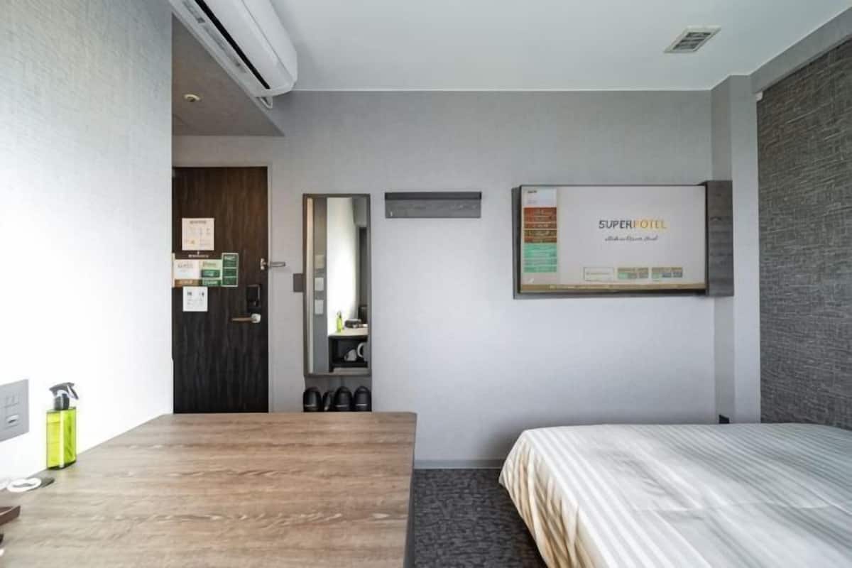 A hotel room with a wooden desk, a bed, a mirror, and a wall-mounted sign.