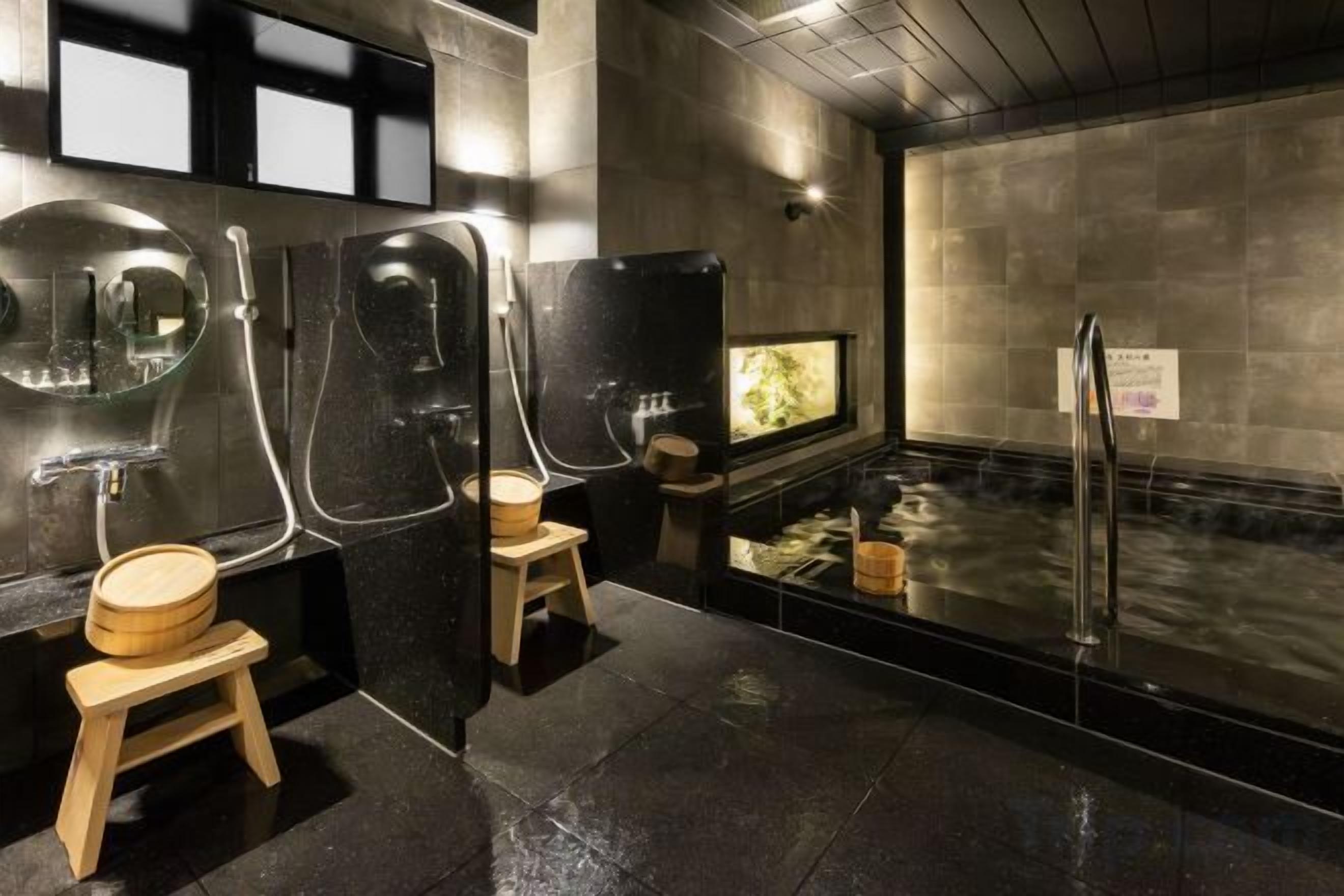 A modern bathroom with a sauna, a glass-enclosed shower, and a wooden stool.
