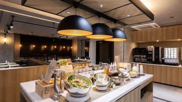 A modern kitchen area with a long counter, various food items, and kitchen appliances.