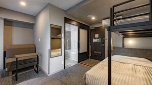 Ein Hotelzimmer mit Stockbetten, einer Schlafcouch, einem Schreibtisch und einem Schiebetürenschrank.