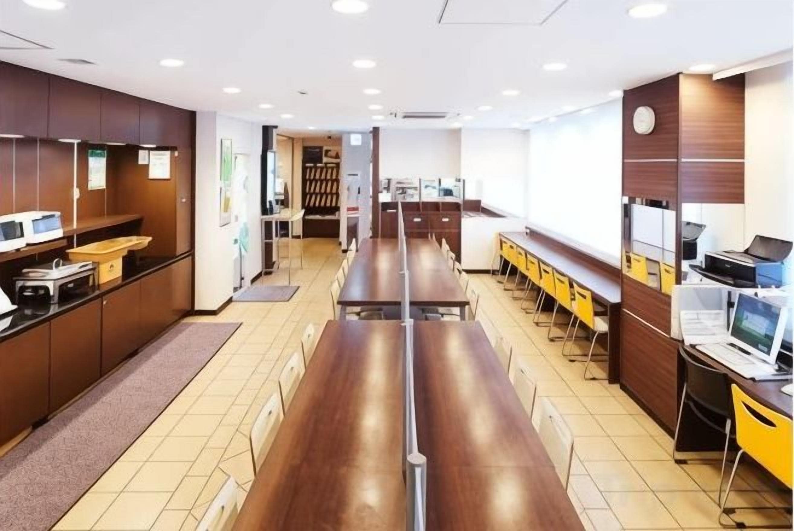 A modern office space with long tables, computers, and a central aisle.