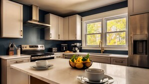Una cocina moderna con armarios blancos, electrodomésticos de acero inoxidable, un amplio ventanal y un cuenco de limones en la encimera.