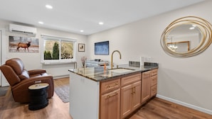 A modern kitchen with a built-in island, wooden cabinets, and a large mirror. - The Jewel Box - Fully Updated Downtown Condo w/ AC (Sandpoint)