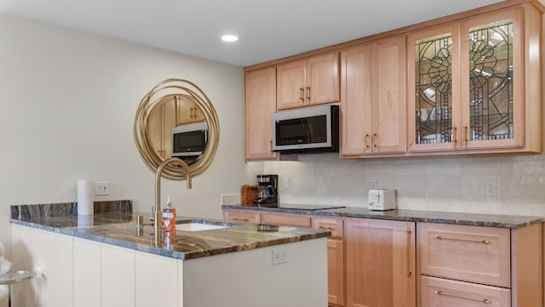 A kitchen with wooden cabinets, a microwave, a coffee maker, and a sink. - The Jewel Box - Fully Updated Downtown Condo w/ AC (Sandpoint)