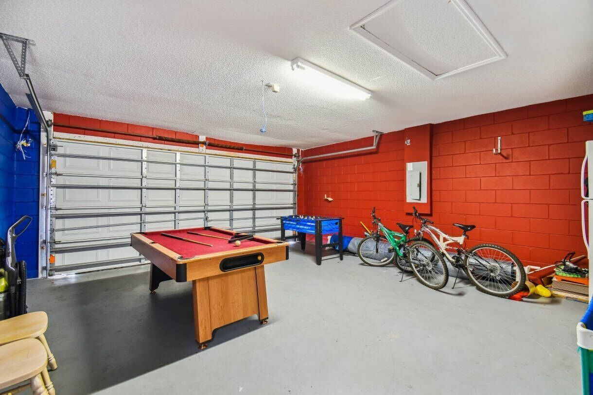 A garage with a pool table, bicycles, and a blue foosball table.