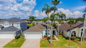 Un barrio residencial con casas unifamiliares, céspedes cuidados y palmeras.