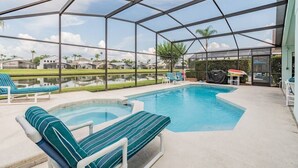 Una piscina al aire libre con sillones de descanso y una zona techada.