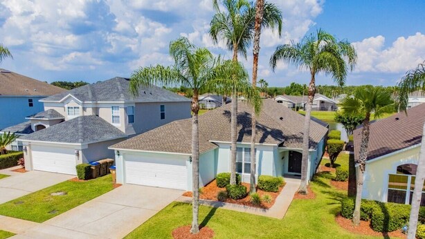 Zona residencial con casas que tienen jardines, palmeras y un cielo despejado.