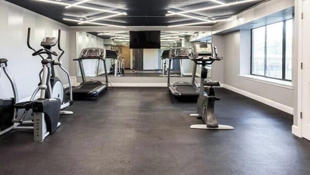 A gym with treadmills, stationary bikes, and elliptical machines. - Charming 2-bedroom apartment with fitness room and AC in Southfield (Southfield)