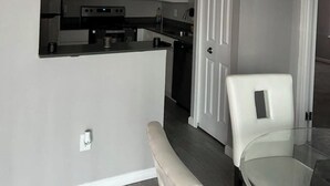A compact kitchen with white cabinets, a black countertop, and a stainless steel range hood. - Charming 2-bedroom apartment with fitness room and AC in Southfield (Southfield)