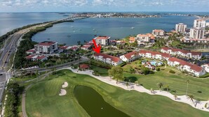 Eine Luftaufnahme einer Küstenlandschaft mit mehreren Gebäuden, einem Golfplatz und einer Marina.