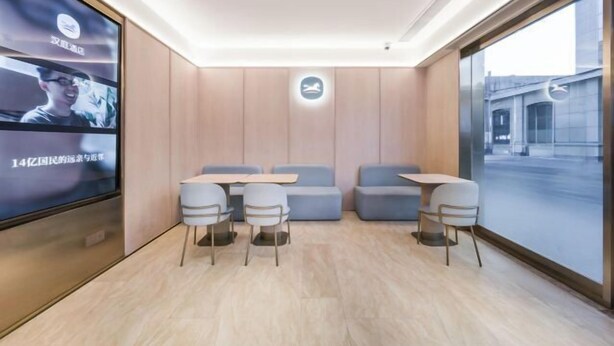 Un espace de détente moderne, doté de sièges et de tables, d’un grand écran diffusant du contenu et offrant une vue à travers une grande fenêtre.