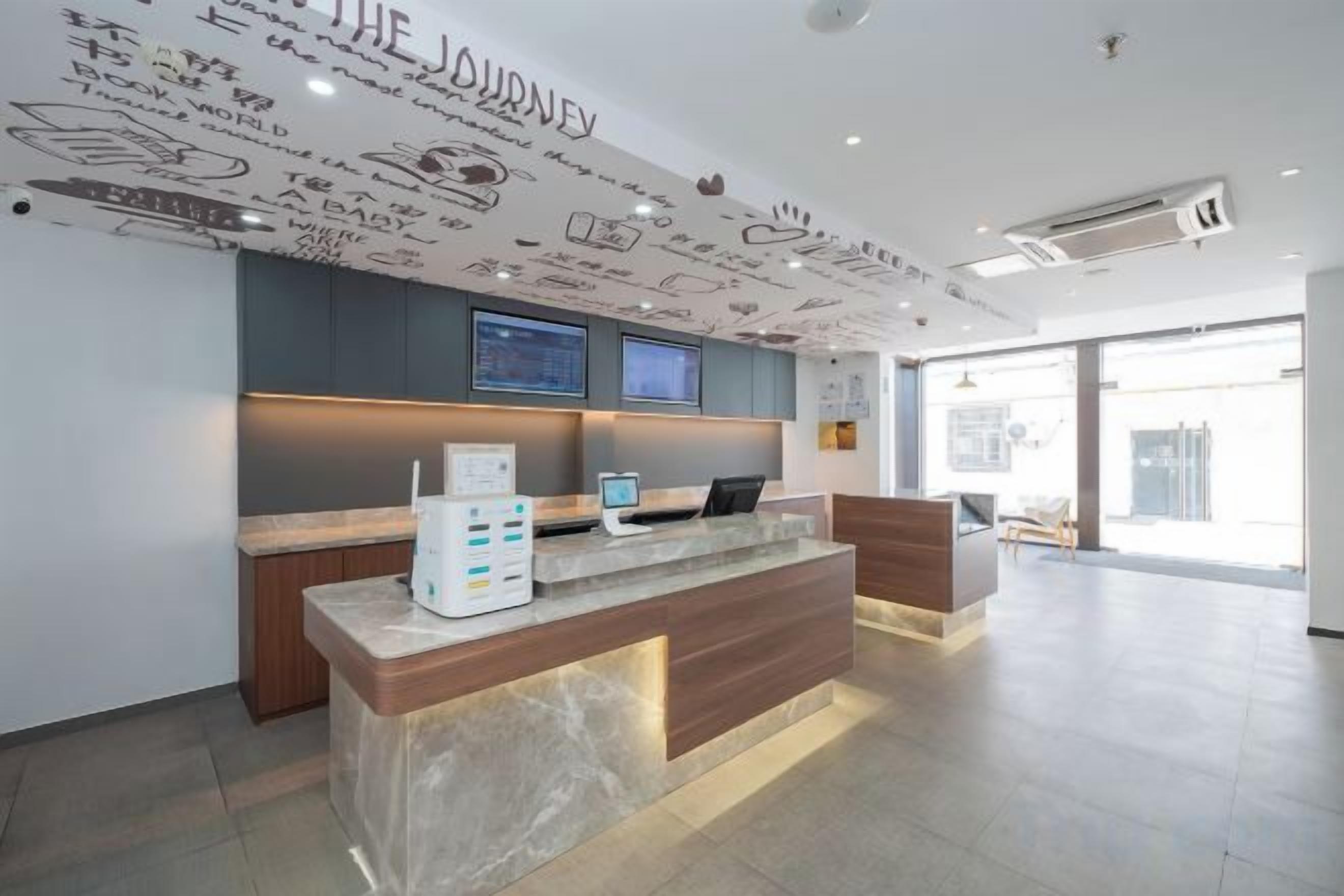 A reception area with a marble counter, a digital display, and a wall with doodle-style text.