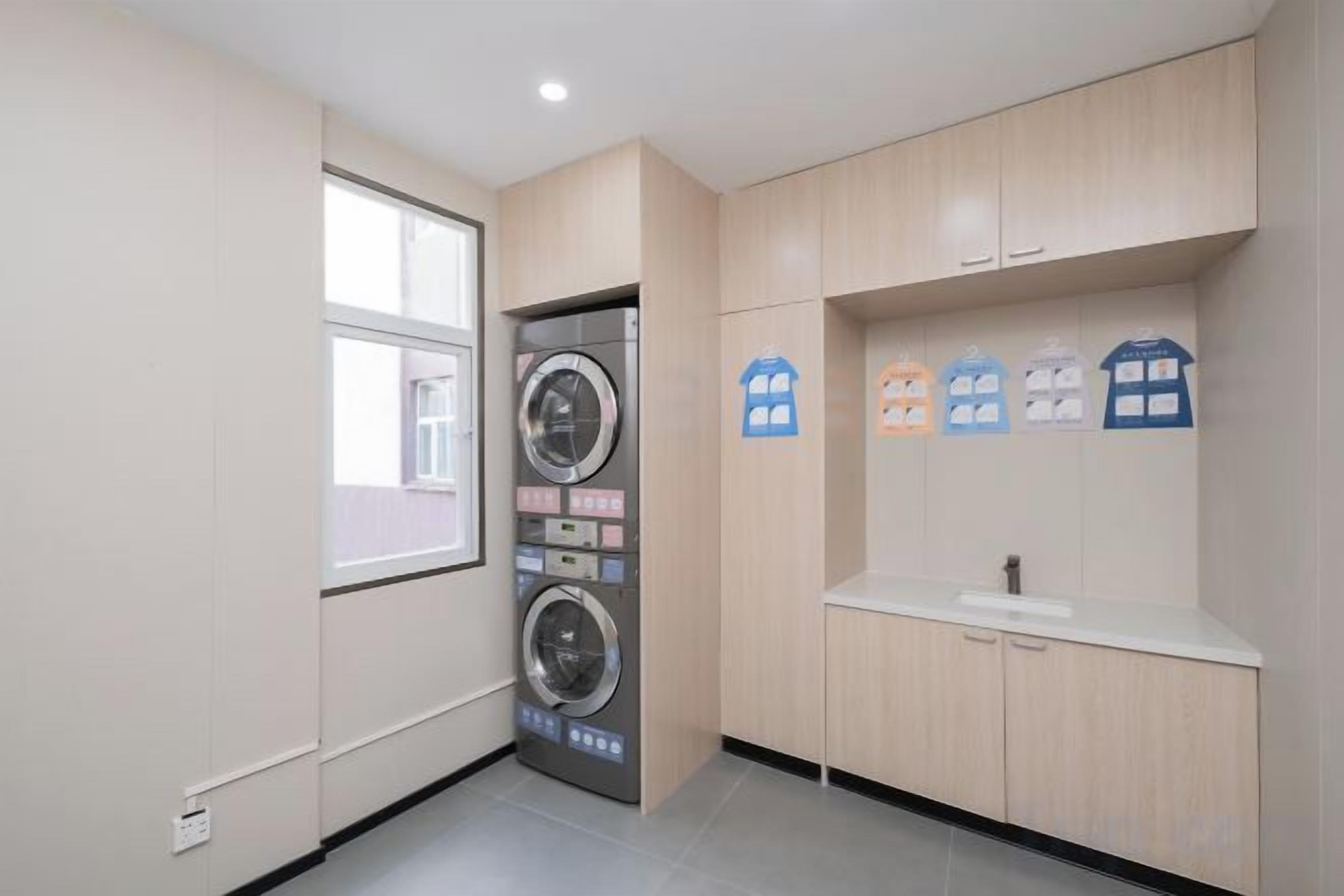 A laundry room with a washing machine, a sink, and wooden cabinets.