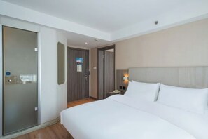 Una camera d'albergo con un letto, un comodino, un telefono e una porta che dà su un'altra stanza.