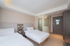 Una camera d'albergo con due letti, un comodino con un telefono, un armadio e uno specchio.
