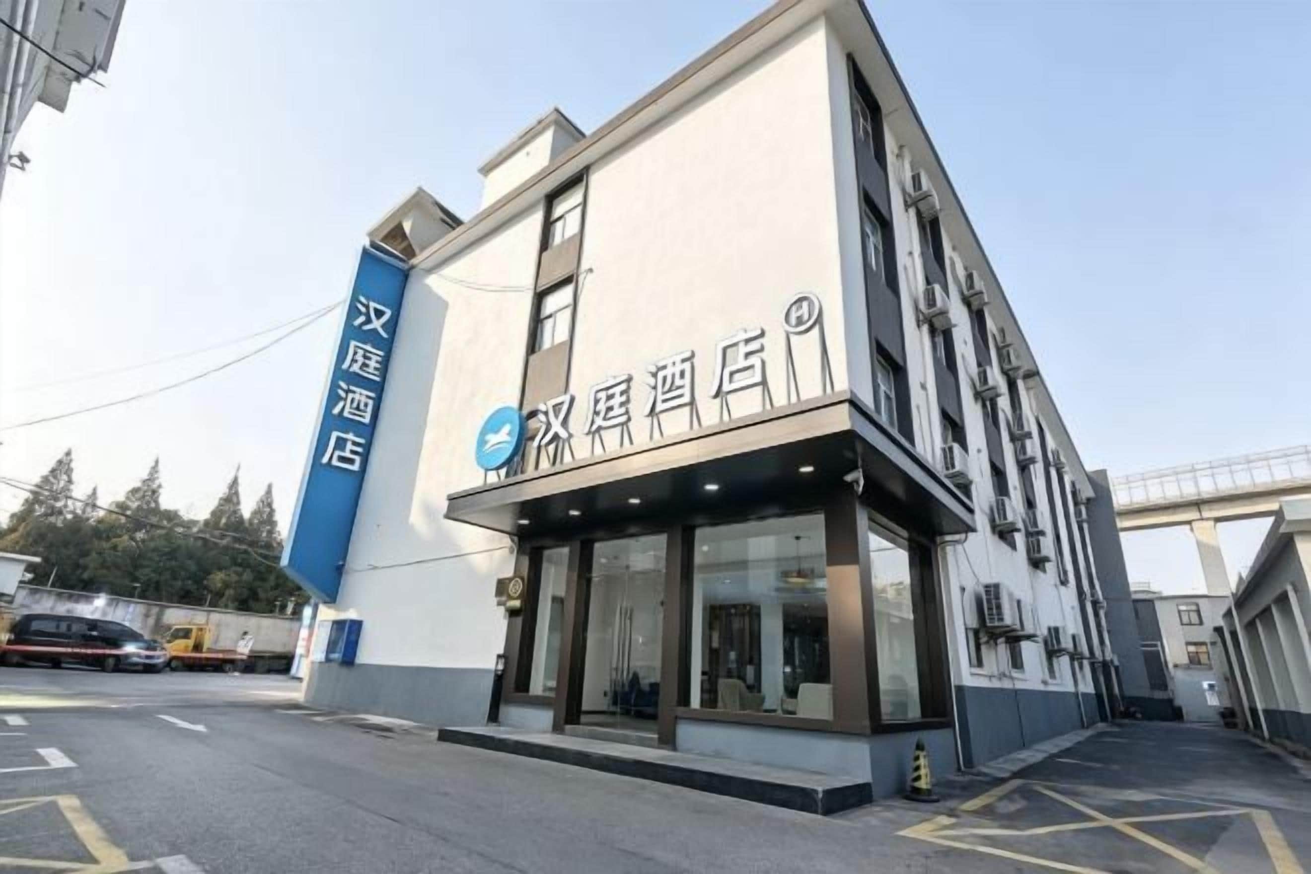A hotel with a modern facade, large windows, and a blue sign on the side.