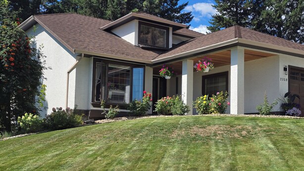 A modern two-story house with a covered porch, a garage, and a well-maintained lawn.