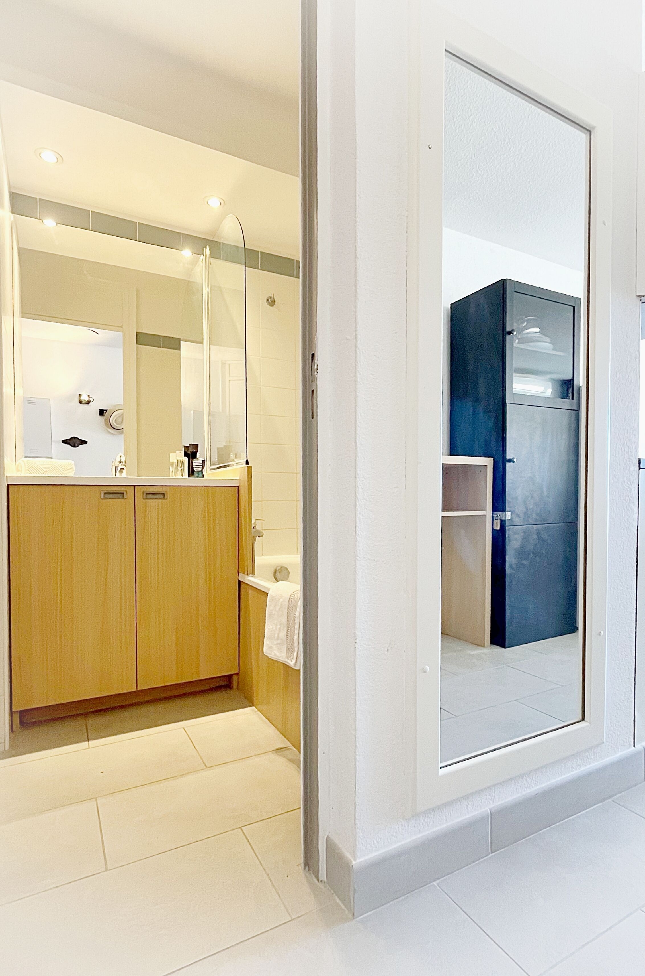 Un baño moderno con tocador de madera, un espejo grande y cabina de ducha con mampara de vidrio.