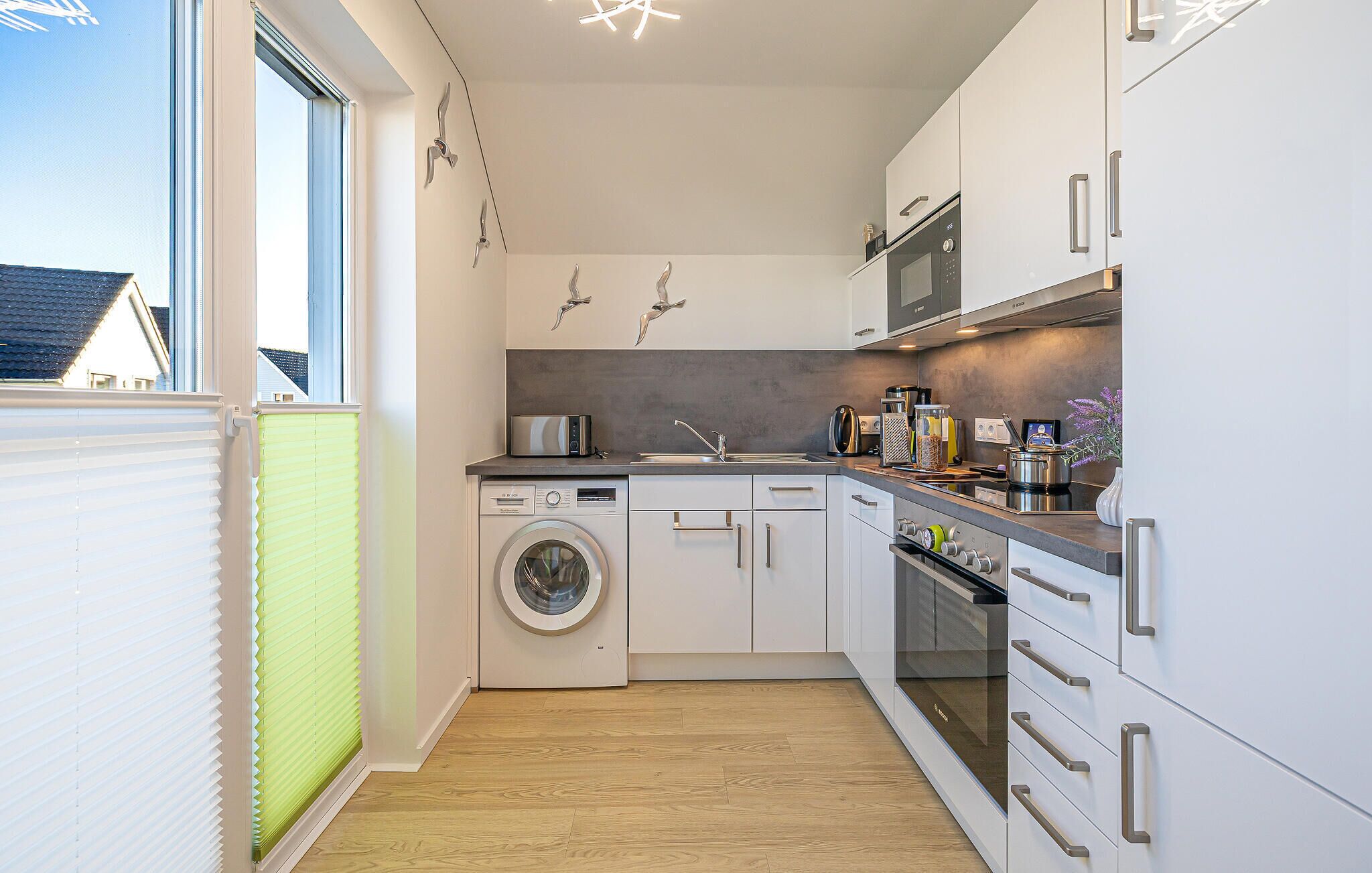 A compact kitchen with a washing machine, microwave, and oven.