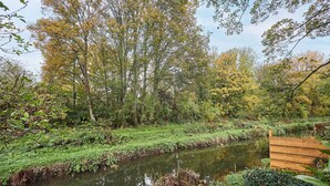 A serene riverside setting with a wooden fence and lush greenery. - Host Stay Foss Court (York)